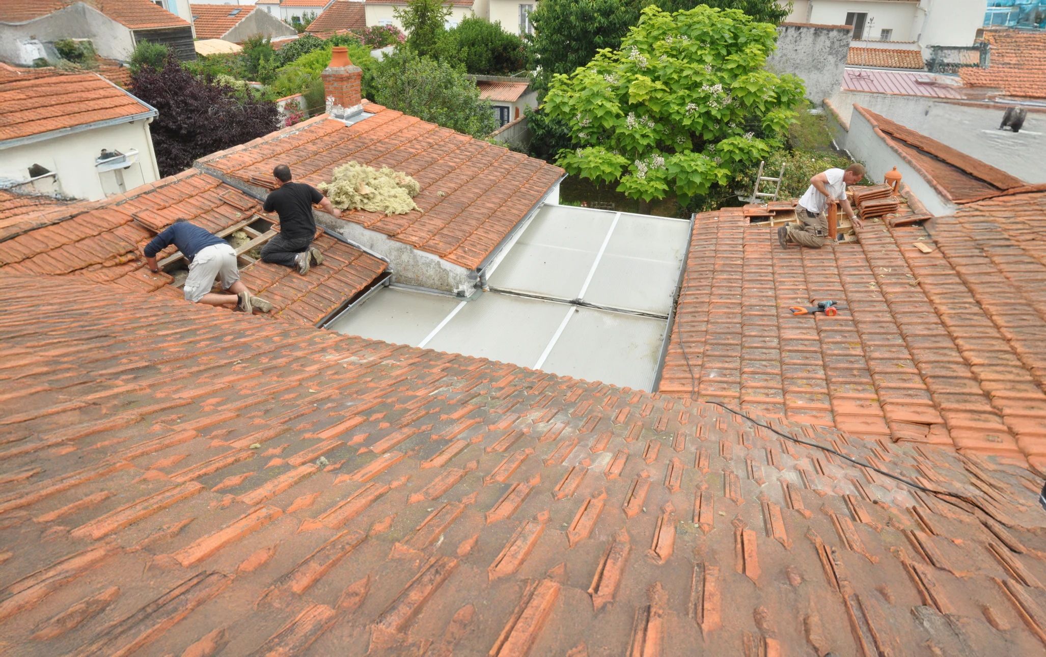 Ouvriers effectuant réparation de toiture en tuiles terre cuite sur maison résidentielle