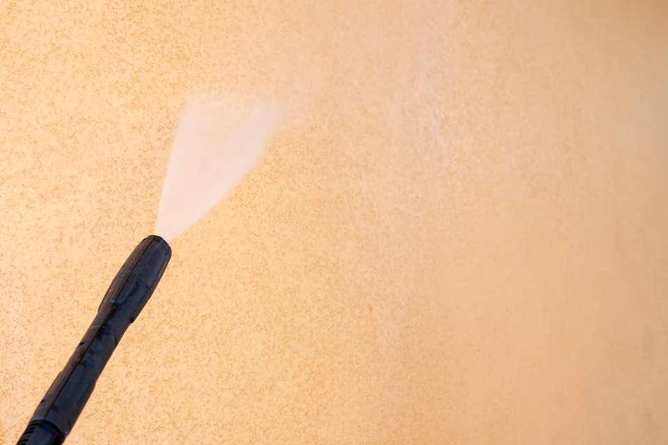 Scène extérieure montrant un nettoyage de sol en béton avec traces de saleté jaunâtre